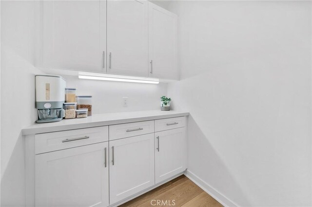 bar featuring white cabinets and light hardwood / wood-style floors