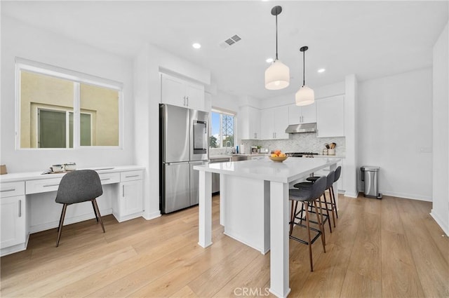 kitchen with white cabinetry, stainless steel appliances, and a kitchen island