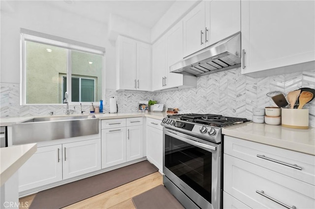 kitchen with sink, decorative backsplash, stainless steel gas range, and white cabinets