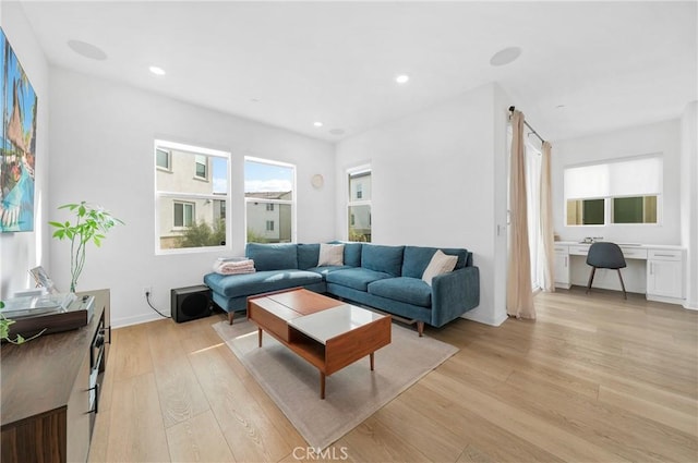 living area featuring recessed lighting, light wood-style floors, and built in desk