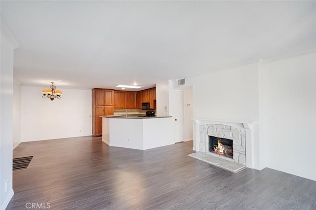 unfurnished living room with a high end fireplace, dark hardwood / wood-style flooring, a chandelier, and ornamental molding