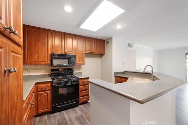 kitchen with black appliances, tasteful backsplash, sink, kitchen peninsula, and light wood-type flooring