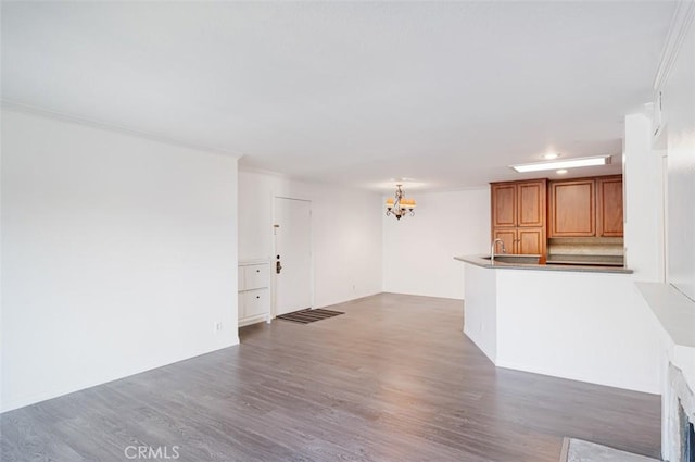 unfurnished living room featuring dark wood-type flooring, ornamental molding, and a chandelier