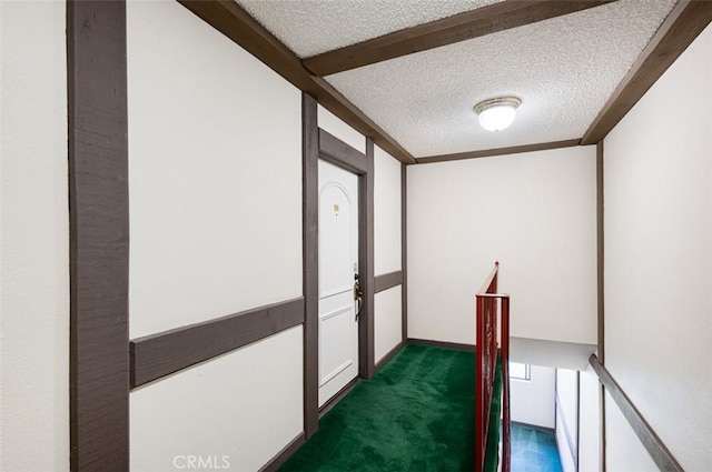 hall featuring a textured ceiling and dark carpet