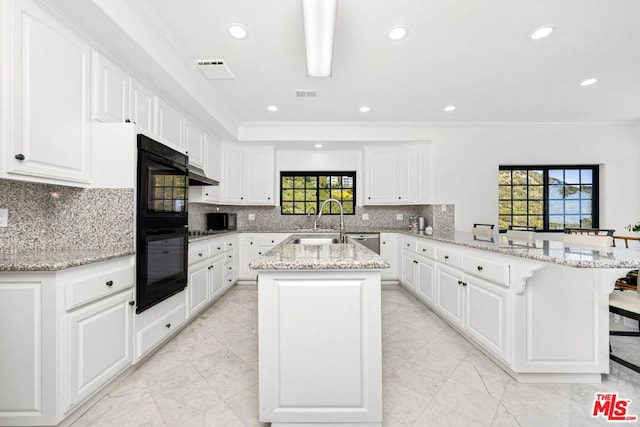 kitchen featuring white cabinetry, kitchen peninsula, a breakfast bar, and light stone countertops