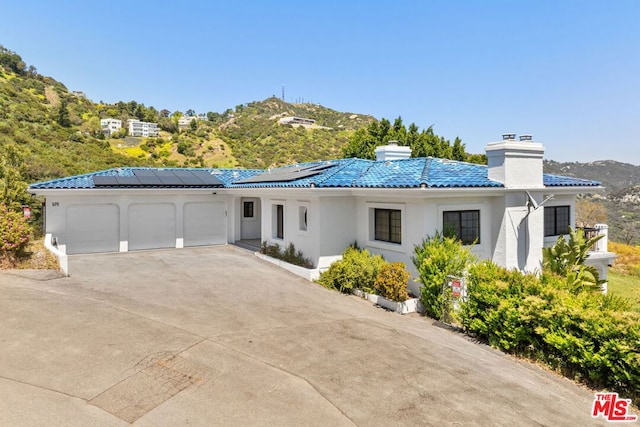 view of front of house with a mountain view, solar panels, and a garage