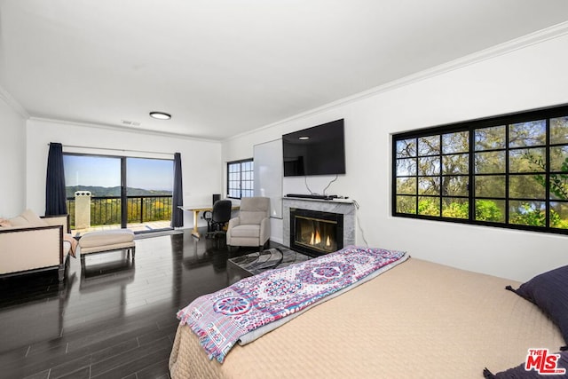 bedroom featuring access to outside, a premium fireplace, crown molding, and multiple windows