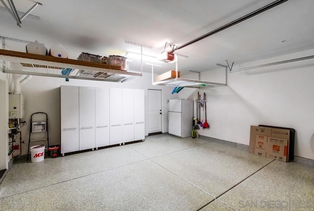 garage featuring tankless water heater, white fridge, and a garage door opener