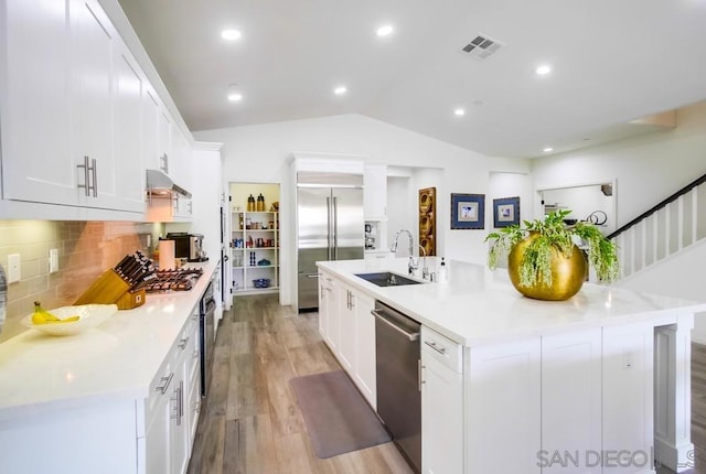 kitchen with stainless steel appliances, a large island with sink, white cabinetry, and sink