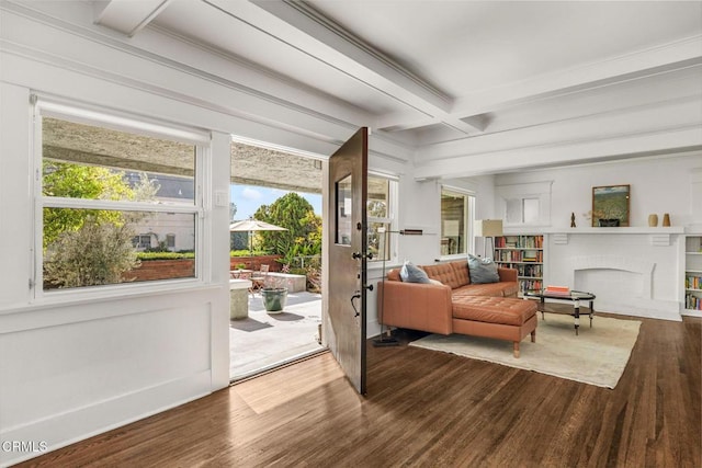 doorway with crown molding, a fireplace, hardwood / wood-style floors, and beamed ceiling