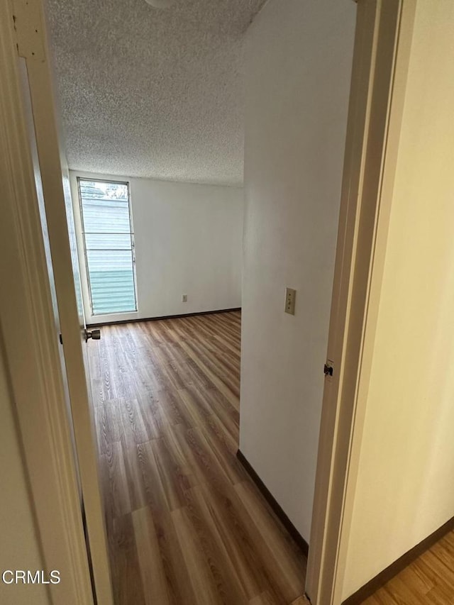 hall featuring a textured ceiling and hardwood / wood-style flooring