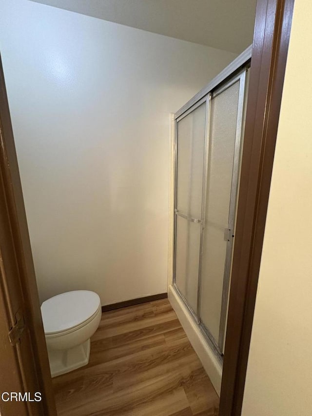 bathroom featuring hardwood / wood-style flooring, toilet, and walk in shower