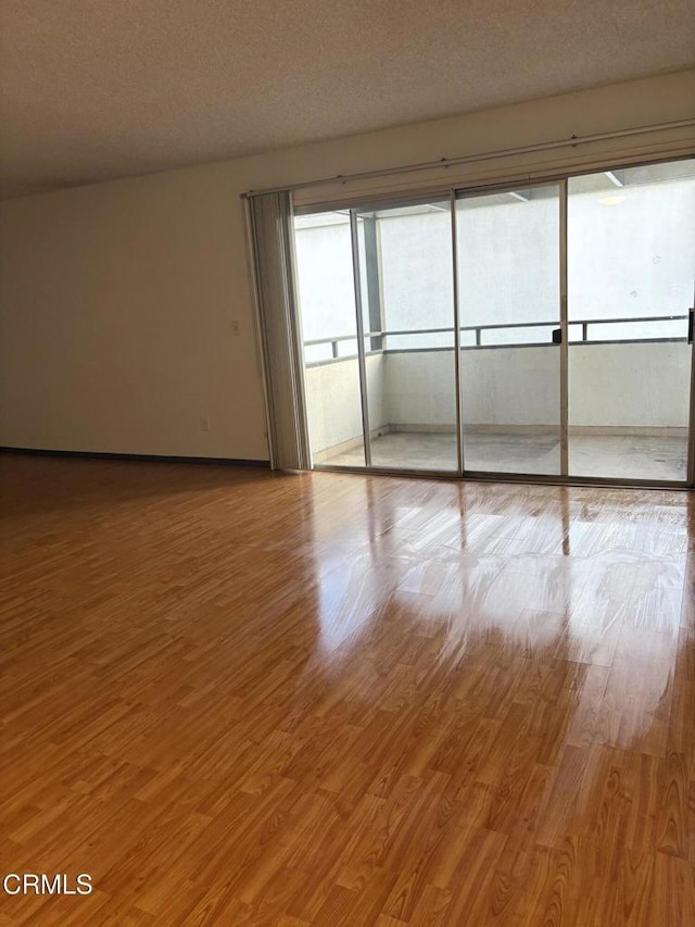 unfurnished room featuring light hardwood / wood-style floors and a textured ceiling