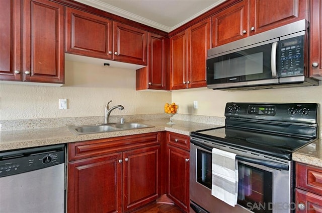 kitchen with appliances with stainless steel finishes, crown molding, light stone counters, and sink