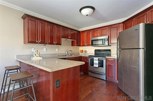 kitchen with dark hardwood / wood-style floors, sink, crown molding, appliances with stainless steel finishes, and a breakfast bar area