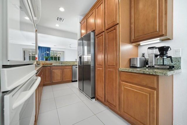 kitchen featuring stainless steel appliances, light tile patterned floors, and light stone counters