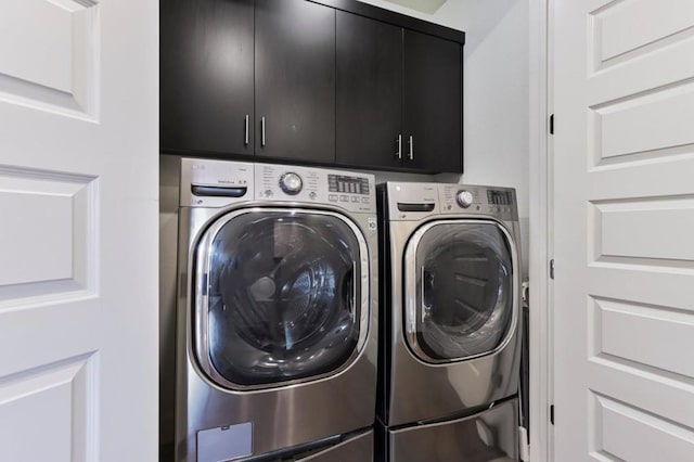 clothes washing area with cabinets and washing machine and dryer