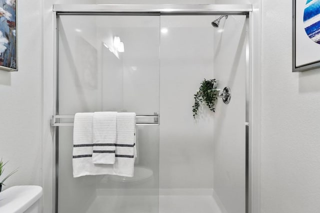 bathroom with toilet and a shower with door