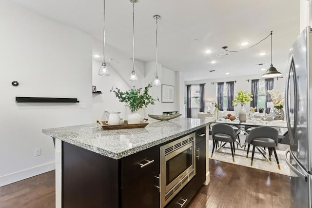 kitchen with dark wood-type flooring, dark brown cabinets, stainless steel appliances, and a center island