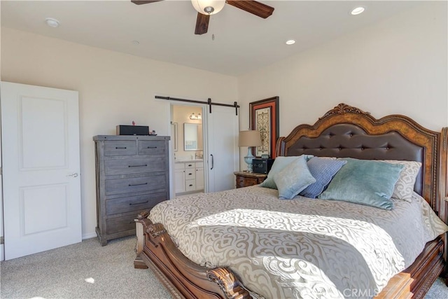 carpeted bedroom featuring ceiling fan, ensuite bathroom, and a barn door