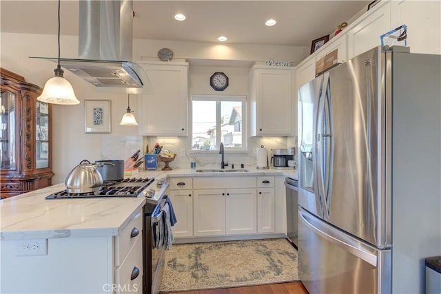 kitchen featuring pendant lighting, appliances with stainless steel finishes, white cabinets, sink, and island range hood