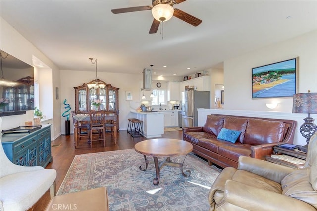 living room with ceiling fan with notable chandelier and dark wood-type flooring