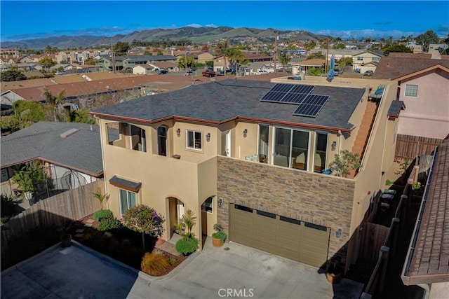 view of front facade featuring a mountain view, solar panels, and a garage