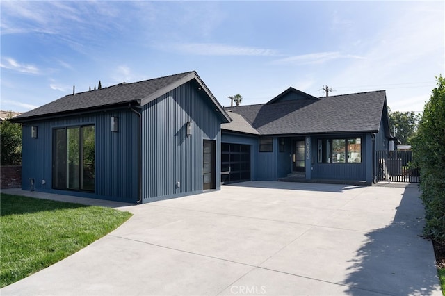 modern inspired farmhouse with a garage, a front yard, driveway, and a shingled roof