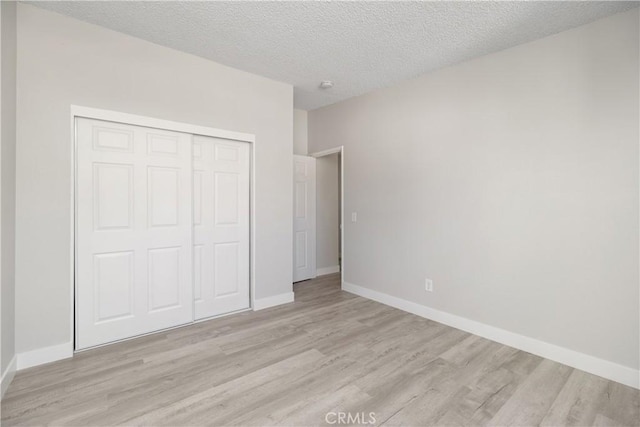 unfurnished bedroom with light wood finished floors, baseboards, and a closet