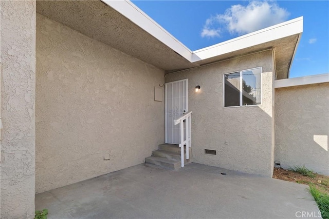 property entrance with crawl space, a patio, and stucco siding