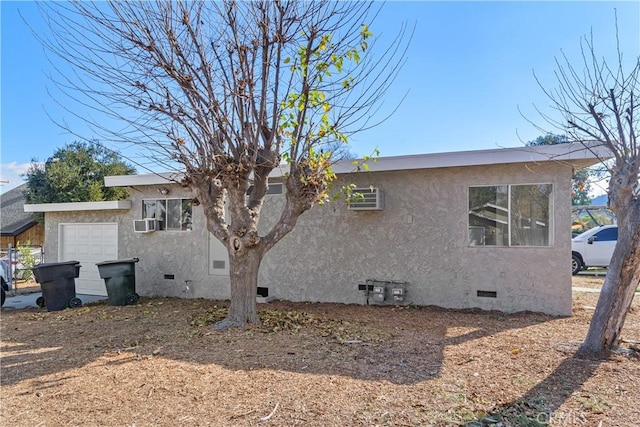 exterior space featuring crawl space, an attached garage, cooling unit, and stucco siding