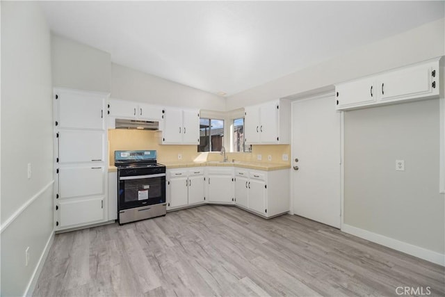 kitchen with light wood-style flooring, under cabinet range hood, white cabinetry, light countertops, and stainless steel range with gas stovetop