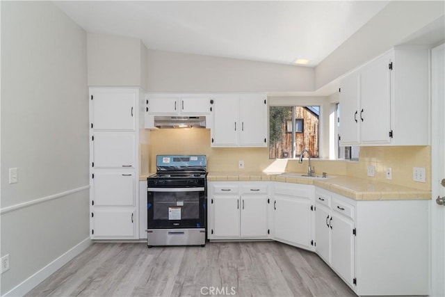 kitchen featuring tasteful backsplash, white cabinets, a sink, gas range, and under cabinet range hood