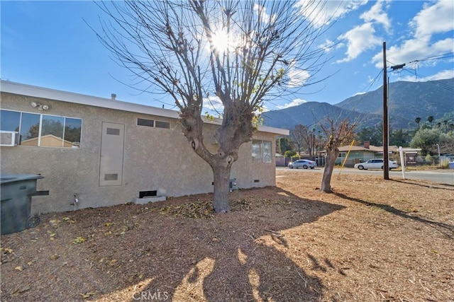 view of property exterior featuring crawl space, a mountain view, and stucco siding