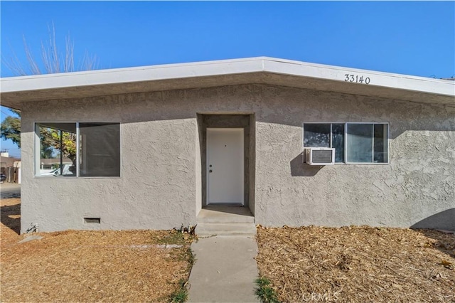 doorway to property featuring crawl space, cooling unit, and stucco siding