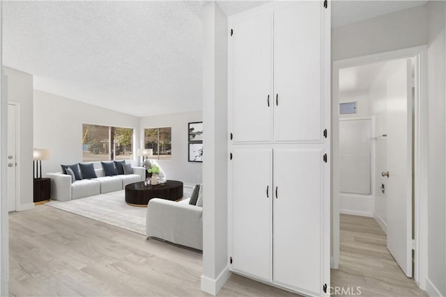 living area with a textured ceiling, light wood finished floors, and baseboards