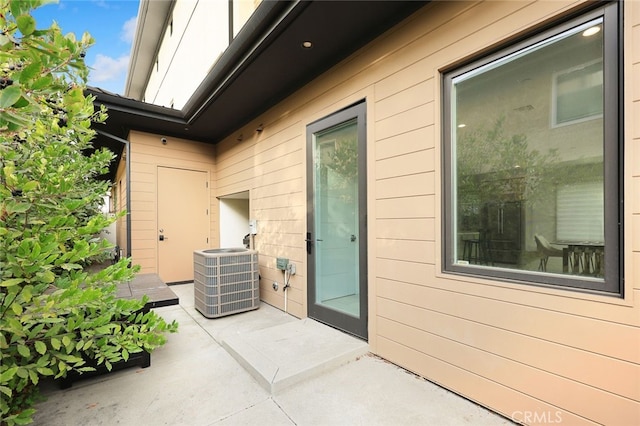 view of exterior entry with a patio area and central air condition unit