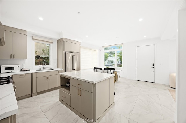 kitchen with sink, gray cabinets, high end refrigerator, and a center island