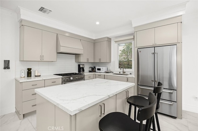 kitchen with a kitchen island, stainless steel appliances, sink, custom range hood, and a breakfast bar area