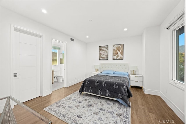 bedroom with connected bathroom and hardwood / wood-style floors