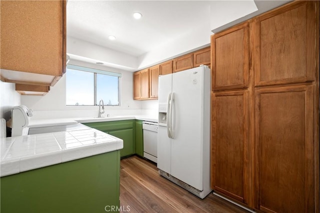 kitchen featuring white appliances, tile counters, dark wood-type flooring, and sink