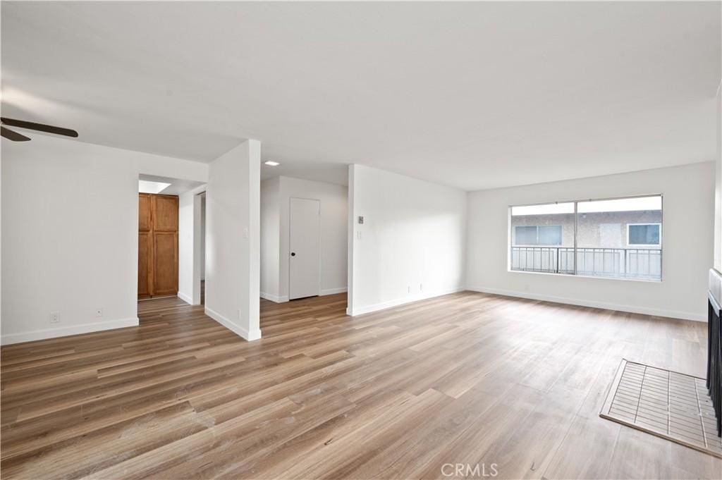 unfurnished living room featuring light hardwood / wood-style flooring, ceiling fan, and a tiled fireplace