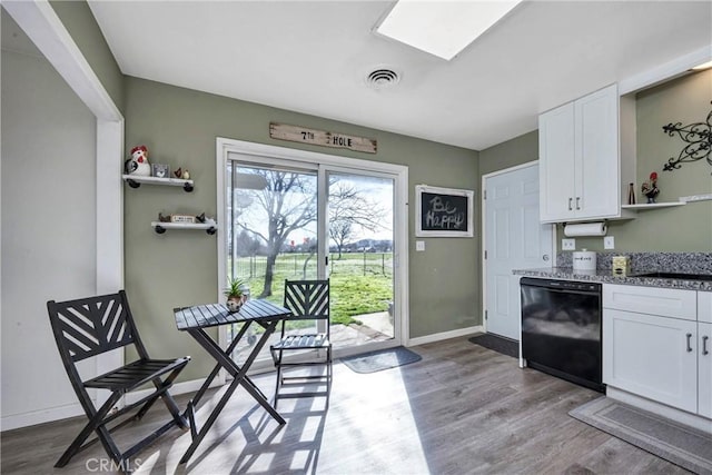 kitchen with light hardwood / wood-style floors, light stone countertops, black dishwasher, and white cabinetry