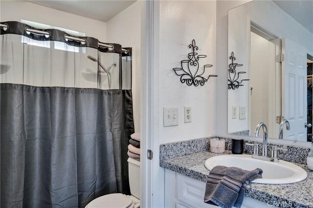 bathroom featuring toilet, vanity, and a shower with shower curtain