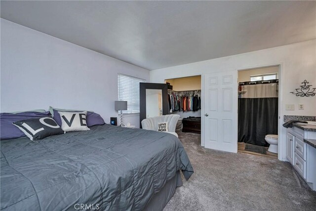 bedroom featuring ensuite bath, carpet, a closet, and a spacious closet