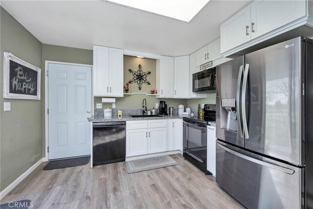 kitchen featuring black appliances, white cabinets, sink, and light hardwood / wood-style flooring