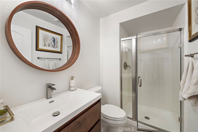 bathroom featuring a shower with shower door, vanity, and toilet