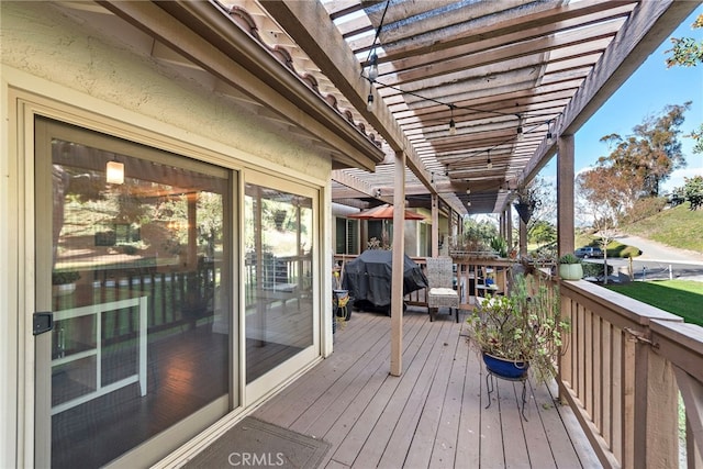 wooden deck featuring area for grilling and a pergola