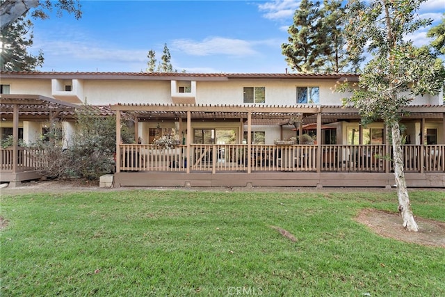 rear view of house featuring a deck, a yard, and a pergola