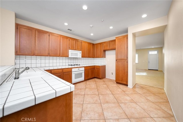 kitchen with white appliances, tasteful backsplash, sink, tile countertops, and light tile patterned floors